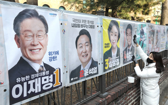 선관위 직원이 서울 종로구 이화동 예술가의집 울타리에 ‘제20대 대통령선거’에 출마하는 후보자들의 선거벽보를 붙이고 있다. 2022.2.18/뉴스1 © News1