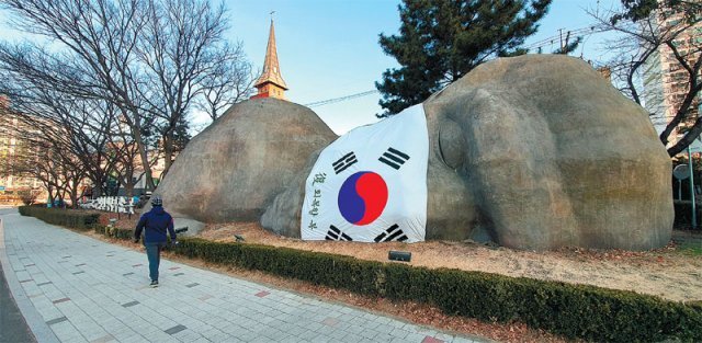 23일 대구 달서구 상화로에 설치돼 있는 원시인 조형물 ‘2만 년의 역사가 잠든 곳’에 태극기 마스크가 씌워져 있어 눈길을 끌고 있다. 대구 달서구 제공