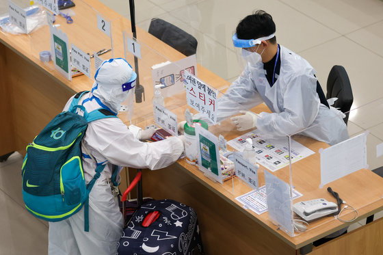 6일 인천국제공항 1터미널 입국장에서 중국 선양에서 온 여행객이 방호복으로 중무장한 채 여권을 보여주고 있다. 2022.3.6/뉴스1 © News1