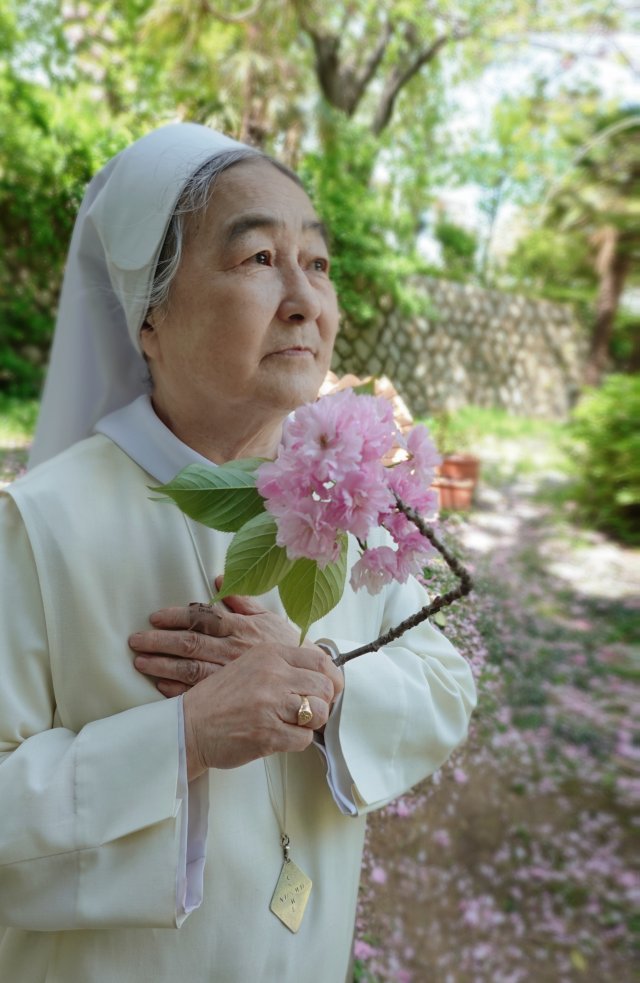 바람에 날려 떨어진 겹벚꽃을 들고 있는 이해인 수녀.
