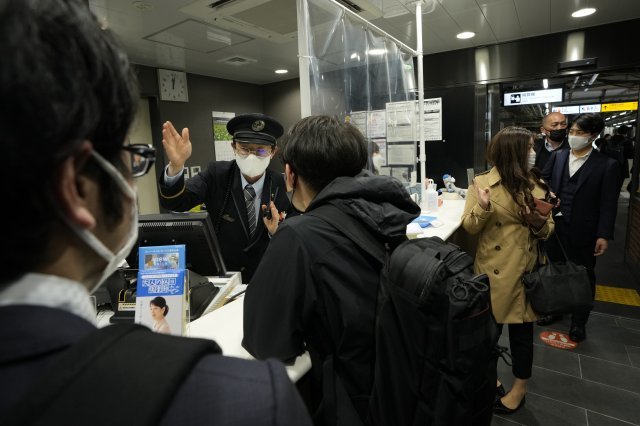 17일 오전 일본 도쿄역에서 역장이 승객들에게 지진으로 운행이 중단됐음을 알리고 있다. AP 뉴시스