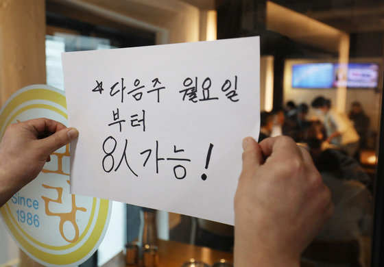 사적모임 제한이 6인에서 8인으로 조정된 18일 서울의 한 식당에서 주인이 8인 가능 안내문을 써 붙이고 있다. 2022.3.18/뉴스1