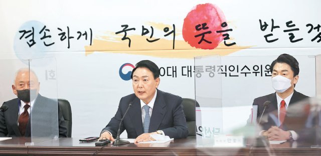 尹 손글씨 활용한 현수막 걸고… 윤석열 대통령 당선인이 18일 서울 종로구 대통령직인수위원회 사무실에서 첫 전체회의를
 주재하고 있다. 뒤로는 윤 당선인이 직접 ‘겸손하게 국민의 뜻을 받들겠습니다’라고 쓴 손글씨를 활용해 만든 현수막이 걸렸다. 
왼쪽부터 김한길 인수위 국민통합위원장, 윤 당선인, 안철수 인수위원장. 사진공동취재단