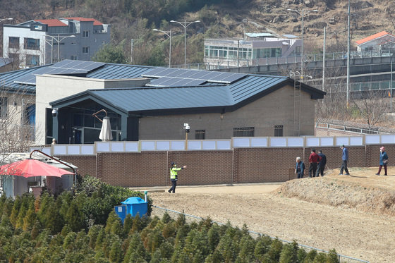 15일 오후 대구 달성군 유가읍 박근혜 전 대통령 사저를 찾은 관람객들이 담벼락 뒤편 언덕에 올라 사저를 구경하자 사저 경호·경비업무를 담당하는 경찰관이 이를 제지하고 있다. 2022.3.15/뉴스1 © News1