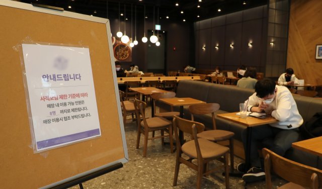 사회적 거리두기가 완화된 21일 부산 부산진구 한 카페직원이 거리두기 관련 안내문을 붙이고 있다. 이번 완화조치로 사적모임은 기존 6명에서 8명으로 추가 되었다. 2022.3.21/뉴스