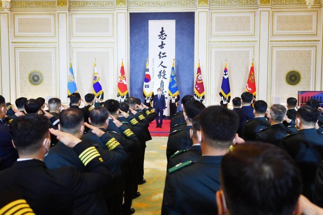 문재인 대통령이 준장진급자 들에게 경례를 받고 거수경례로 답하고 있다.  너머로 보이는 것은  안중근 의사의 ‘지사인인 살신성인’ 유묵. 청와대사진기자단