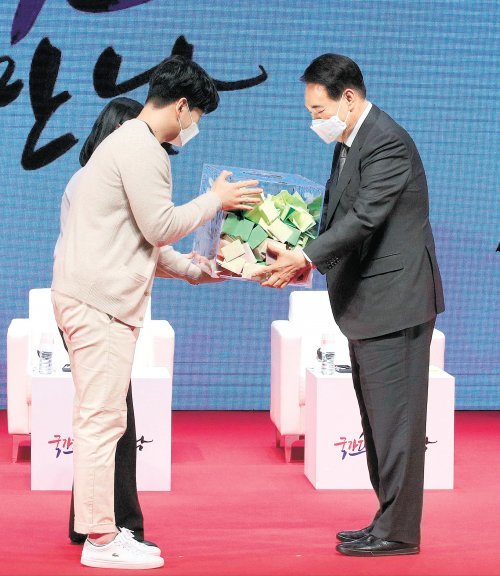 윤석열 대통령 당선인(오른쪽)이 31일 서울 강남구 한국무역협회에서 열린 ‘청년무역 국가대표와의 만남’에서 청년 무역인들의 소망이 적힌 쪽지를 전달받고 있다. 인수위사진기자단