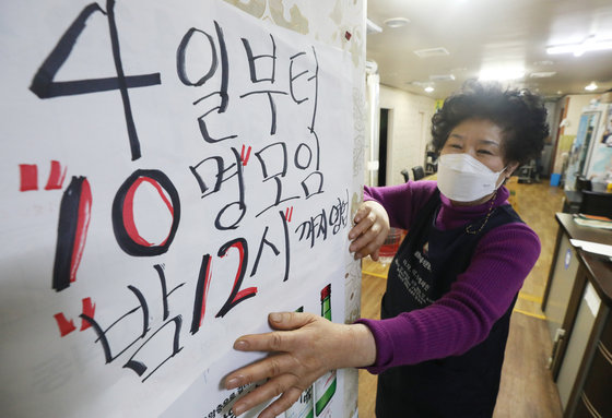 신종 코로나바이러스 감염증(코로나19) 사회적 거리두기가 발표된 1일 서울 한 음식점에서 점주가 변경된 사회적 거리두기 문구를 붙이고 있다.  © News1