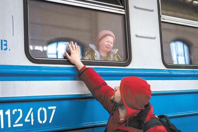 지난달 22일 우크라이나 서부 르비우역에서 한 남성이 폴란드행 열차에 어린 자녀를 태운 뒤 작별인사를 하고 있다. 르비우=AP 뉴시스