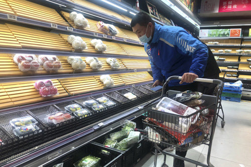 지난달 30일 중국 상하이의 슈퍼마켓에서 한 배달원이 부분적으로 비어 있는 진열대의 물건을 고르고 있다. 상하이=AP/뉴시스