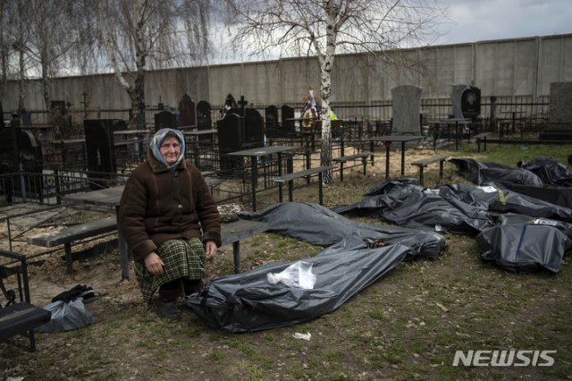 12일(현지시간) 우크라이나 부차에서 나디야 할머니(70)가 러시아군에 살해된 아들 바딤(40)의 시신 옆에 허망하게 앉아 있다. 2022.04.13. [부차=AP/뉴시스]
