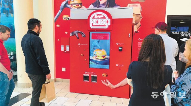 지난달 31일(현지 시간) 미국 뉴저지주 저지시티의 쇼핑몰에 설치된 붉은색의 햄버거 자판기 ‘로보 버거’를 시민들이 흥미롭게 구경하고 있다. 결제 후
약 7분이 지나면 로봇이 직접 조리한 따끈한 햄버거를 먹을 수 있다. 뉴욕=유재동 특파원 jarrett@donga.com