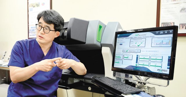 송교영 서울성모병원 로봇수술센터장이 로봇수술 시뮬레이터 앞에서 포즈를 취하고 있다. 5개 분야의 45개 프로그램이 내장된 이 시뮬레이터 테스트를 통과하지 못하면 수술에 임할 수 없다고 송 교수는 설명했다. 서울성모병원 제공