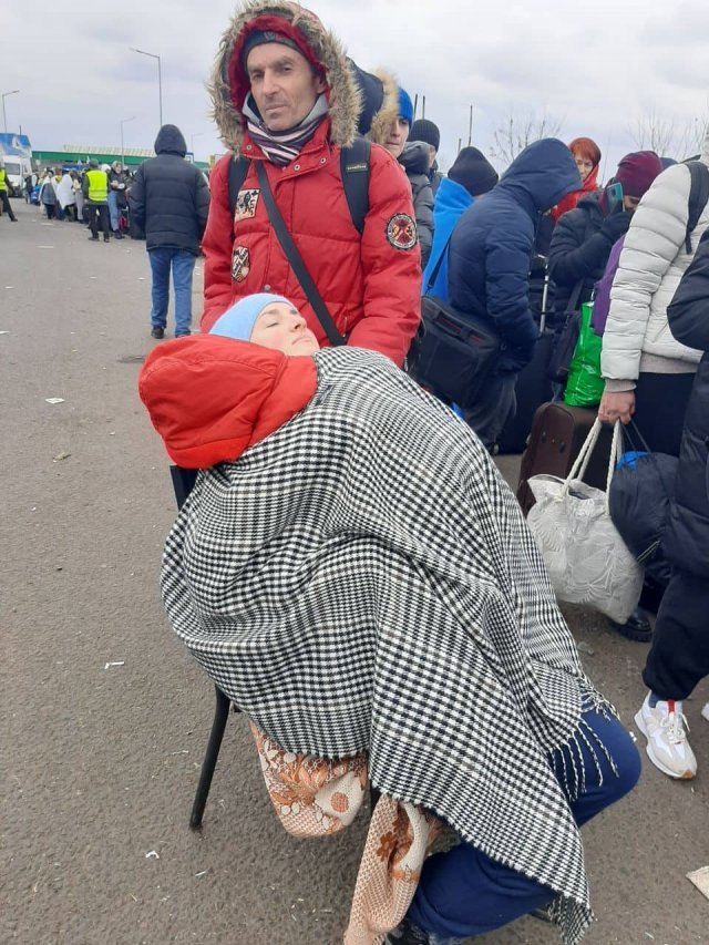지난달 4일 우크라이나에서 폴란드로 넘어가는 국경에서 티우텐코 씨가 남편(빨간색 외투를 입은 남성)과 작별 인사를 한 뒤 망토로 두 딸을 덮은 모습. 네 식구가 함께 찍은 마지막 사진이다.