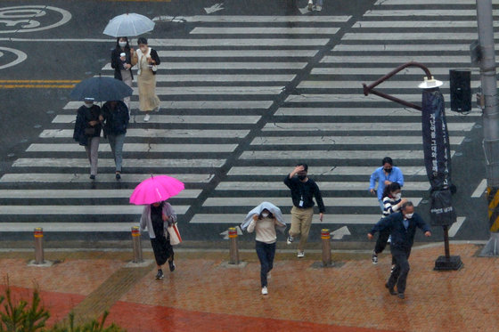 비가 내린 26일 오후 경북 포항시청 앞 횡단보도를 건너던 시민들이 옷과 손으로 머리를 가린 채 비를 피하고 있다.2022.4.26/뉴스1
