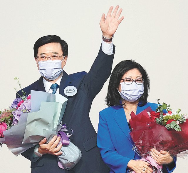 8일 홍콩 행정장관 선거에서 단독 출마 후 당선된 존 리 전 정무사장(왼쪽)이 부인과 함께 꽃다발을 들고 승리를 자축하고 있다. 홍콩=AP 뉴시스