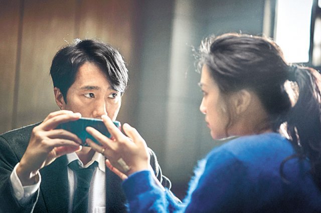 영화 ‘헤어질 결심’에서 해준(박해일·왼쪽)이 서래(탕웨이)를 수사하던 중 함께 휴대전화를 보고 있다. CJ ENM 제공