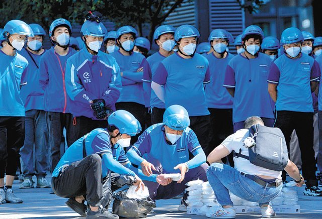 1일 중국 수도 베이징의 한 건물 앞에서 파란 헬멧을 쓴 배달 기사들이 마스크 배분을 위해 기다리고 있다. 코로나19 신규 확진자 급증세가 줄어들자 베이징 당국은 이날 일부 지역에 대한 봉쇄 완화를 발표했다. 베이징=AP 뉴시스