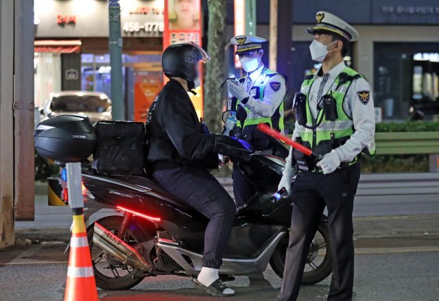 지난달 30일 서울 광진구 자양사거리 인근에서 경찰관이 차량 및 오토바이 등 이륜차 운전자를 대상으로 음주단속을 하고 있다. 경찰은 오토바이와 전동킥보드 등 이륜차에 대한 특별단속을 두 달간 시행한다. 뉴스1