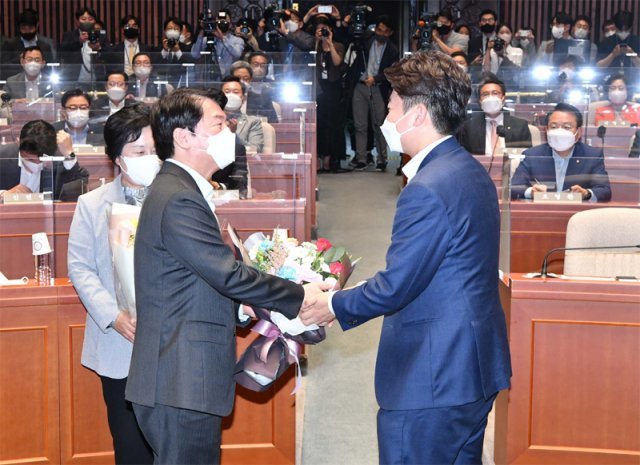 “당선 축하” 겉으론 웃고 있지만… 국민의힘 이준석 대표(오른쪽)가 14일 서울 여의도 국회에서 열린 국민의힘 의원총회에서 같은 당 안철수 의원에게 보궐선거 당선을 축하하며 꽃다발을 전달하고 있다. 사진공동취재단