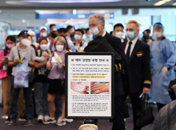 27일 오전 인천국제공항 제1터미널 입국장에 해외 입국자들이 검역을 받기 위해 대기하고 있다. 입국자들 앞에 원숭이두창 관련 안내문이 세워져 있다. 공동취재