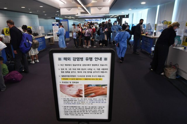 인천국제공항 제1여객터미널 입국장에서 탑승객들이 검역을 받기 위해 대기하고 있는 가운데 원숭이 두창 안내문이 게시되어 있다. 사진공동취재단
