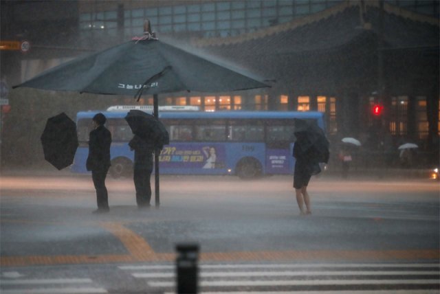 ‘물폭탄’ 한반도 서쪽을 중심으로 시간당 30∼50mm의 폭우가 쏟아진 23일 오후 서울 종로구 광화문광장 인근에서 시민들이 집중 호우 속에 우산을 쓰고 이동하고 있다. 뉴시스