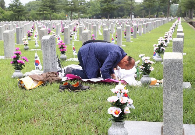 6.25 전쟁 발발 72주년을 하루 앞둔 24일 서울 동작구 국립서울현충원 6.25 전사자 묘역에서 유가족이 절을 하고 있다.