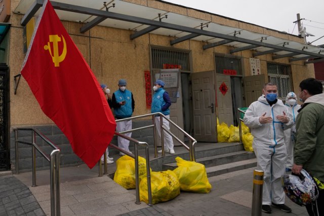 17일 중국 베이징의 봉쇄 구역 밖에서 시 근로자들이 중국 공산당 깃발과 유해 폐기물 쓰레기봉투 근처에 모여 이야기를 나누고 있다. 2022.03.18. AP/뉴시스