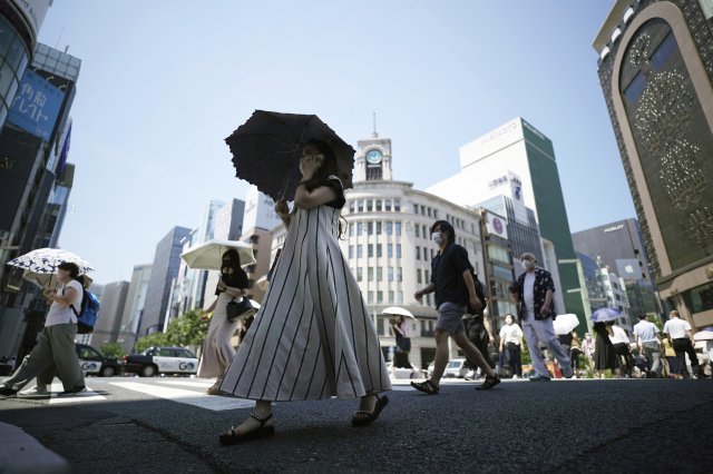 28일 일본 도쿄에서 강렬한 햇빛을 피하고자 양산 쓴 시민들이 건널목을 건너고 있다. 도쿄=AP/뉴시스