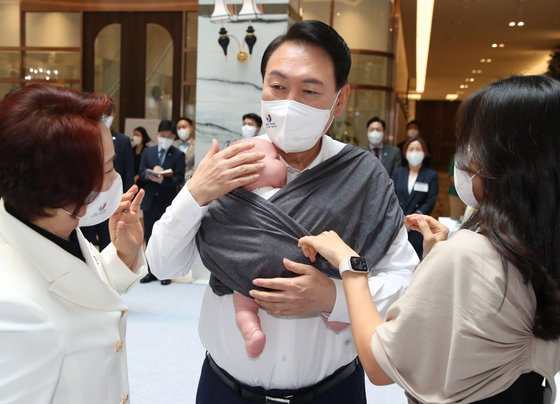 윤석열 대통령이 5일 오후 서울 여의도 중소기업중앙회관에서 제1회 여성기업주간 ‘여성경제인의 날 유공자 정부포상 수여식’에 참석하기 전 육아용품 브랜드 코니바이에린 부스에서 아기띠를 매어보고 있다. 대통령실사진기자단