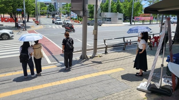 학생들이 횡단보도 인근에서 양산에 기대어 더위를 피하고 있다. 뉴스1