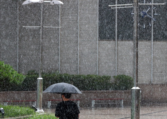 8일 오후 대구 북구 태평로 대구역 앞 광장에서 한 시민이 우산을 펼쳐 함박눈처럼 쏟아지는 소나기를 피하며 발걸음을 재촉하고 있다. 2022.7.8/뉴스1