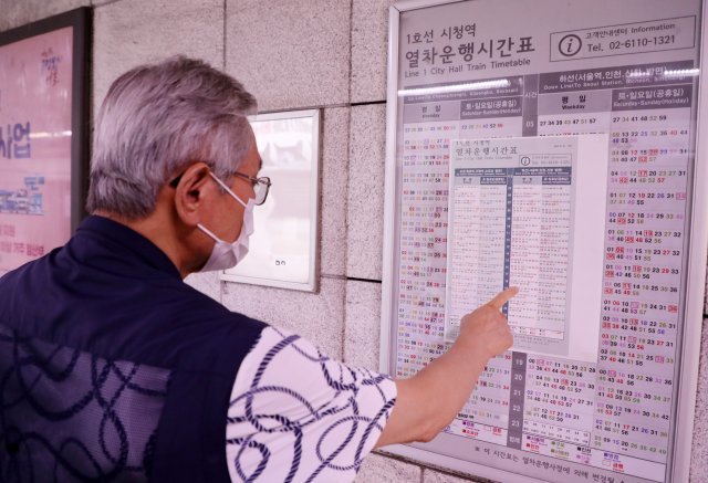 서울교통공사가 내달 일부 환승역을 대상으로 인쇄된 열차 시간표를 시범철거한다. 21일 1호선 서울 시청역에서 한 어르신이 열차운행 시간표를 보고 있다. 전영한 기자 scoopjyh@donga.com