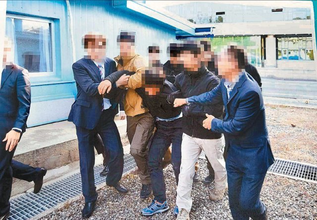 2019년 11월 7일 탈북 어민 중 한 명이 판문점에서 북송을 거부하며 몸부림치자 정부 관계자들이 팔을 붙잡아 제압하고 있다. 통일부는 이 사진을 12일 공개했다. 통일부 제공