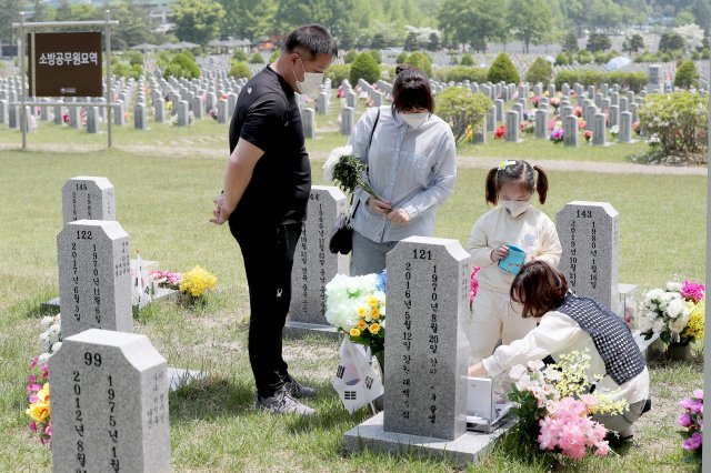 5월 12일 현충원 묘역에서 허승민 소방위 묘비 앞에 놓은 사진을 정돈하는 박현숙(오른쪽)과 가족들.