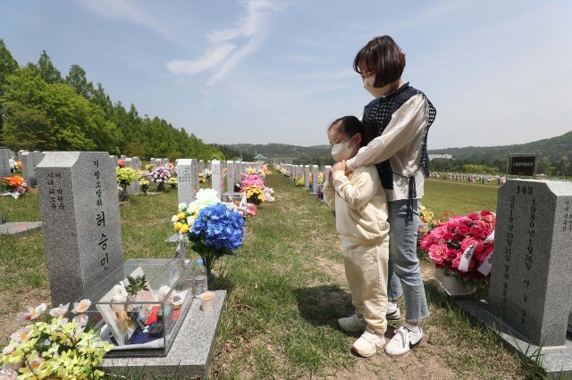 박현숙(오른쪽)이 묘비 앞에서 딸 소윤을 안고 남편을 이야기하고 있다.