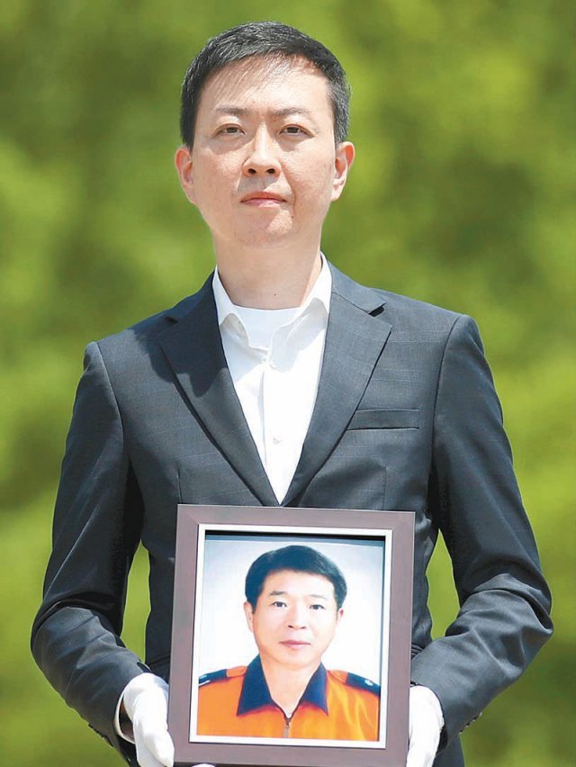 국립대전현충원에서 영욱의 아들 이인이 아버지의 사진을 들고 있는 모습.