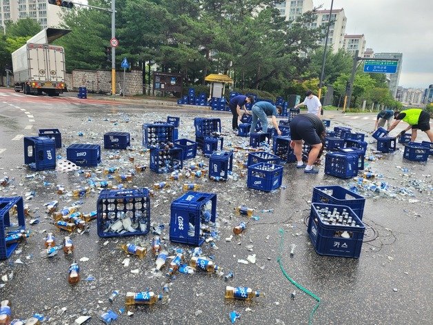 지난 6월 29일 춘천시 퇴계동의 한 사거리에서 5톤 트럭에 실려있던 맥주병 2000여병이 바닥으로 떨어지는 사고가 발생, 길을 가던 시민들이 청소를 돕고 있다.(독자 제공)