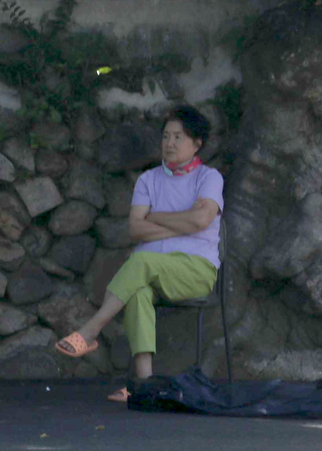 22일 오전 사저를 나온 문재인 전 대통령 부인 김정숙 여사가 이웃한 박진혁씨 집 팽나무 옆에 앉아 주변 상황을 지켜보고 있다. ⓒ News1