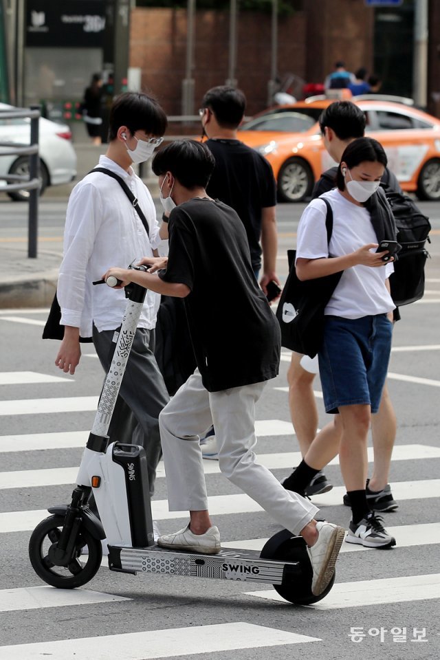 12일 오전 서울 지하철 2호선 강남역 5번 출구 앞에서 한 시민이 전동킥보드를 타고 보행자 사이를 달리며 횡단보도를 건너고 있다. 송은석 기자  silverstone@donga.com