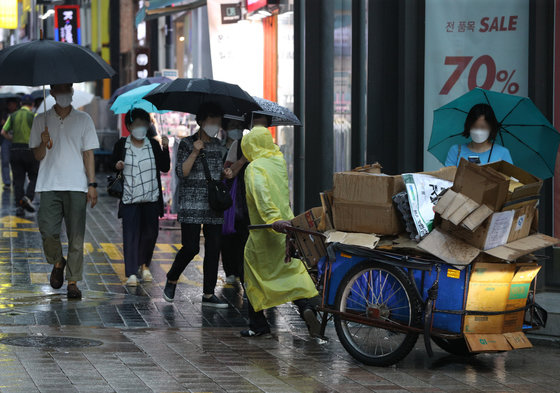 서울 명동거리에서 비옷을 입은 시민이 파지를 담은 리어카를 끌고 있다. 2022.6.23/뉴스1 ⓒ News1