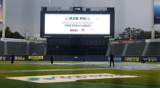 14일 오후 서울 송파구 잠실야구장에서 열린 프로야구 ‘2022 신한은행 SOL KBO리그’ SSG 랜더스와 두산 베어스의 경기, 3회초 갑작스레 내린 비에 관계자들이 우천 경기중단을 결정하고 그라운드에 방수포를 덮고 있다. 2022.8.14/뉴스1