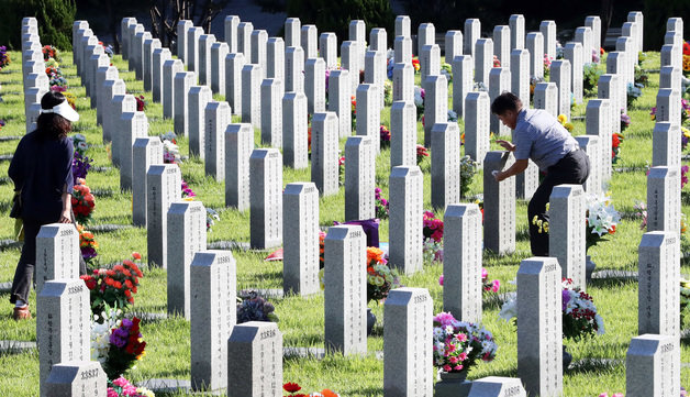 추석 명절 동안 전국 국립묘지가 코로나19 확산 이후 3년만에 전면 개방 결정된 가운데 7일 국립대전현충원을 찾은 시민들이 묘비를 닦으며 성묘하고 있다. 국가보훈처는 추석 연휴 시작일인 9일부터 12일까지 나흘간 전국 12개 국립묘지를 전면 개방하고 온라인 참배도 병행한다고 밝혔다. 2022.9.7/뉴스1