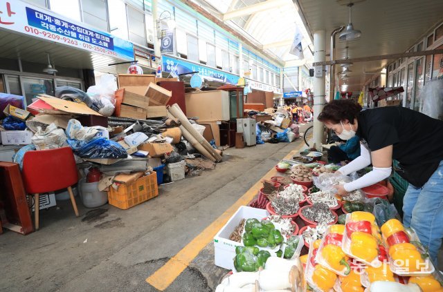 8일 제 11호 태풍 ‘힌남노’의 폭우로 큰 피해를 입은 경북 포항 구룡포 전통시장에서 상인들이 손님을 기다리고 있다. 시장통로에는 수해쓰레기가 쌓여있다.