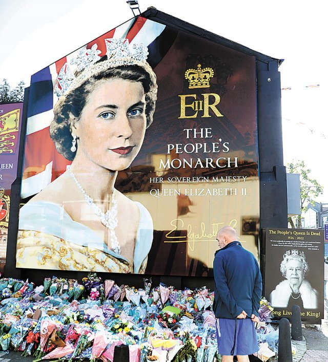 10일(현지 시간) 영국 북아일랜드 벨파스트에 걸린 엘리자베스 2세 여왕의 그림 앞에서 한 시민이 추모하고 있다. 엘리자베스 2세 여왕은 8일 96세 나이로 스코틀랜드 밸모럴성에서 서거했다. 벨파스트=AP 뉴시스