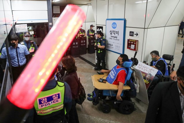 전국장애인차별철폐연대(전장연) 회원들이 13일 오전 서울 용산구 삼각지역에서 열린 ‘제36차 출근길 지하철 탑니다’ 기자회견을 마친 뒤 지하철에 탑승하고 있다. 뉴시스