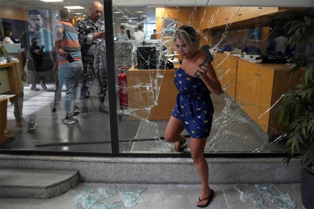 14일 장난감 총을 든 여성이 현금을 훔쳐 간 레바논 베이루트 은행에서 직원이 깨진 창문으로 빠져나오고 있다. 베이루트=AP 뉴시스
