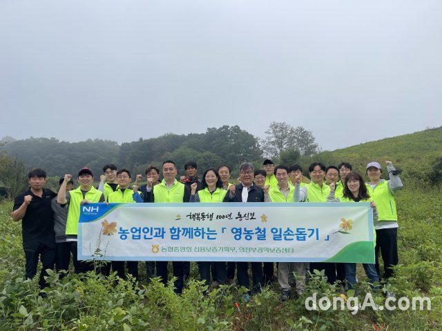 김창선 농신보 신용보증기획부장(사진 앞줄 오른쪽에서 세 번째)을 비롯한 임직원들이 29일 경기 연천 과수농가를 찾아 제초작업 등 농촌 일손돕기에 나서기 전 기념촬영을 하고 있다. 농협 제공