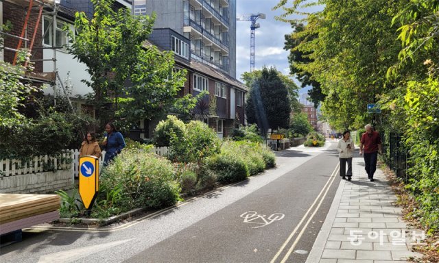 지난달 28일 영국 런던 램버스 지역 ‘복스홀 워크’ 거리에서 시민들이 산책하고 있다. 차도 중앙에 차도 폭을 좁혀 차량 운행 속도를 낮추기 위한 ‘미니 정원’이 설치돼 있다. 런던=김수현 기자 newsoo@donga.com